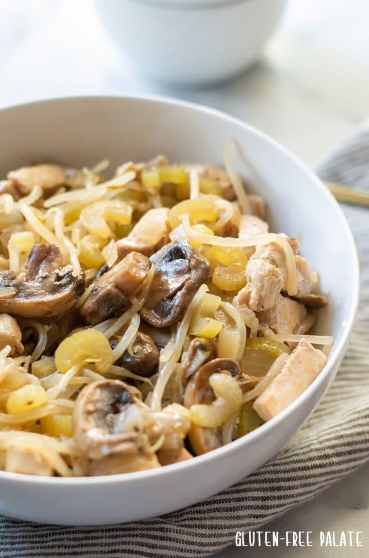 chicken subgum chow mein in a white bowl with a spoon next to a small bowl of subgum