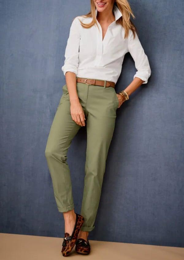 Woman wearing white button up and green chinos showing what to wear on a plane