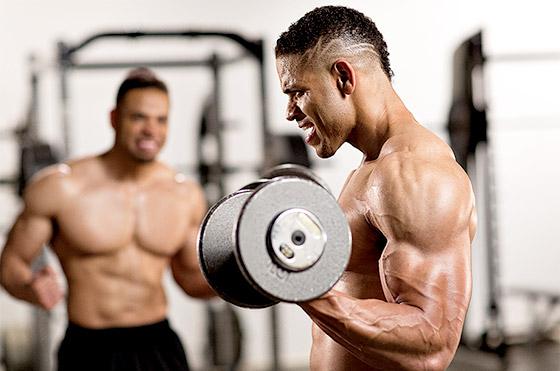One of the Hodgetwins doing biceps curls while the other is motivating him to do more
