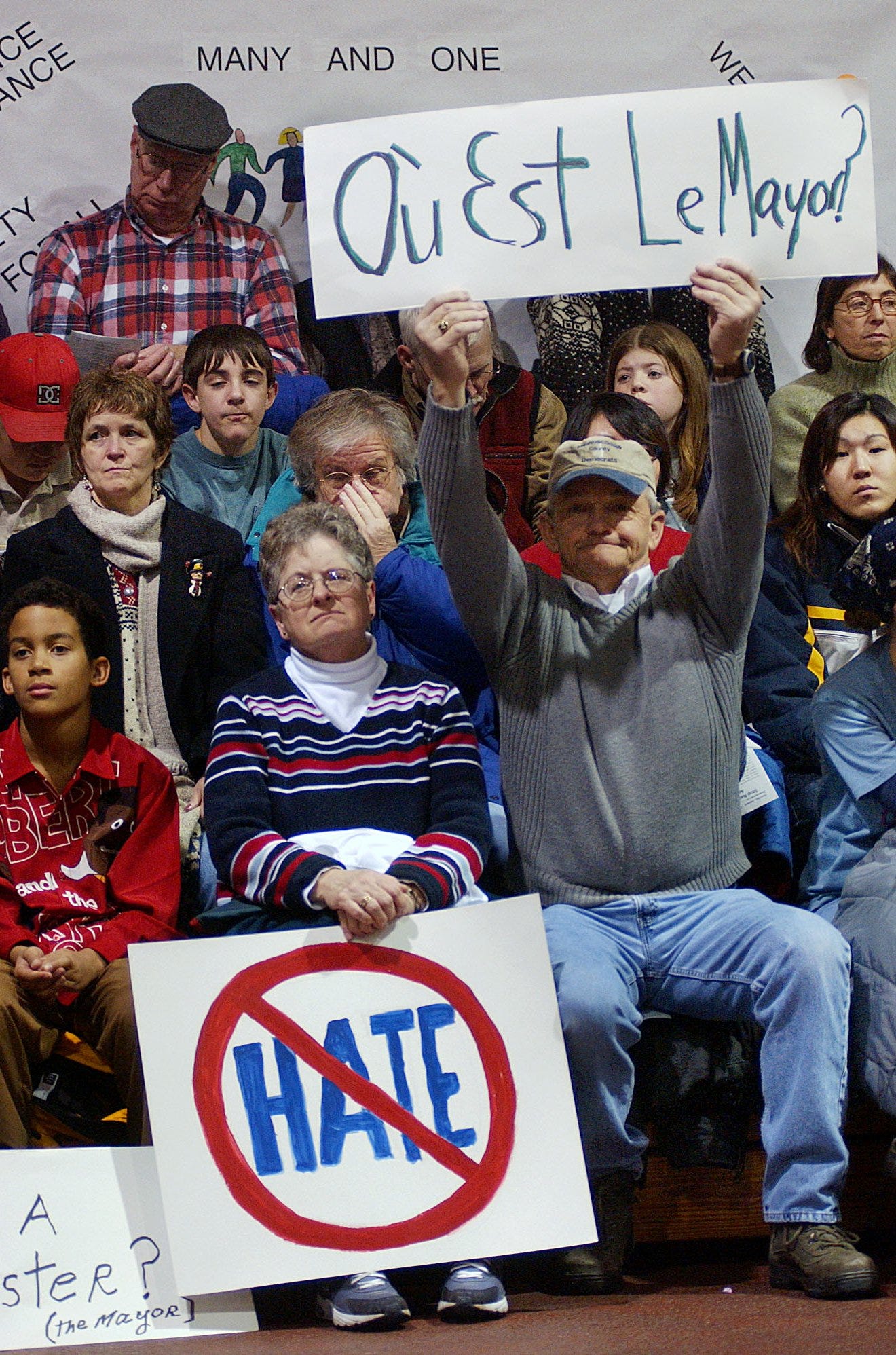 Edward Desgrosseilliers, right, holds a sign in French asking "Where is the mayor?" during a pro-diversity rally at Bates College gymnasium in Lewiston, Maine, Saturday, Jan. 11, 2003.