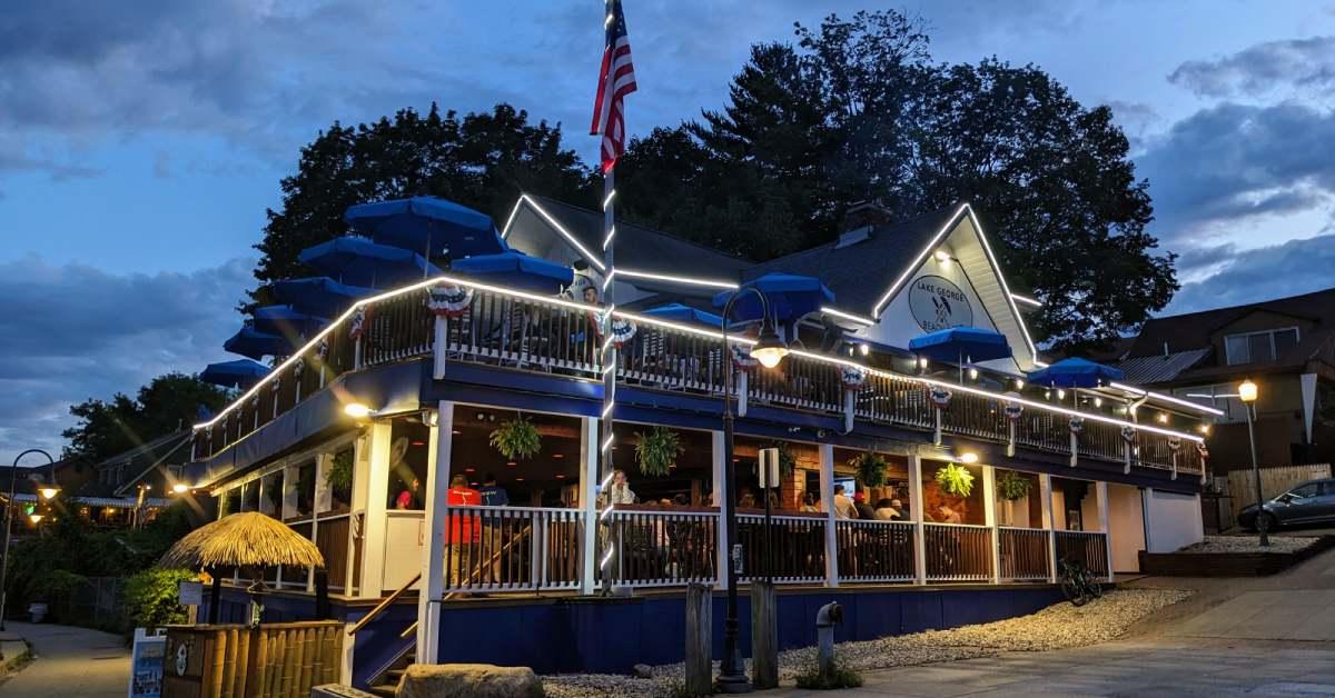 exterior of lake george beach club at dusk, two levels of patios