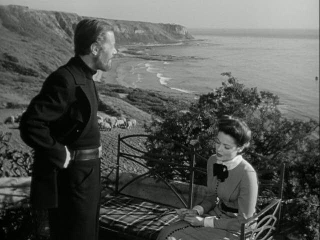 Rex Harrison and Gene Tierney in front of cottage overlooking the sea
