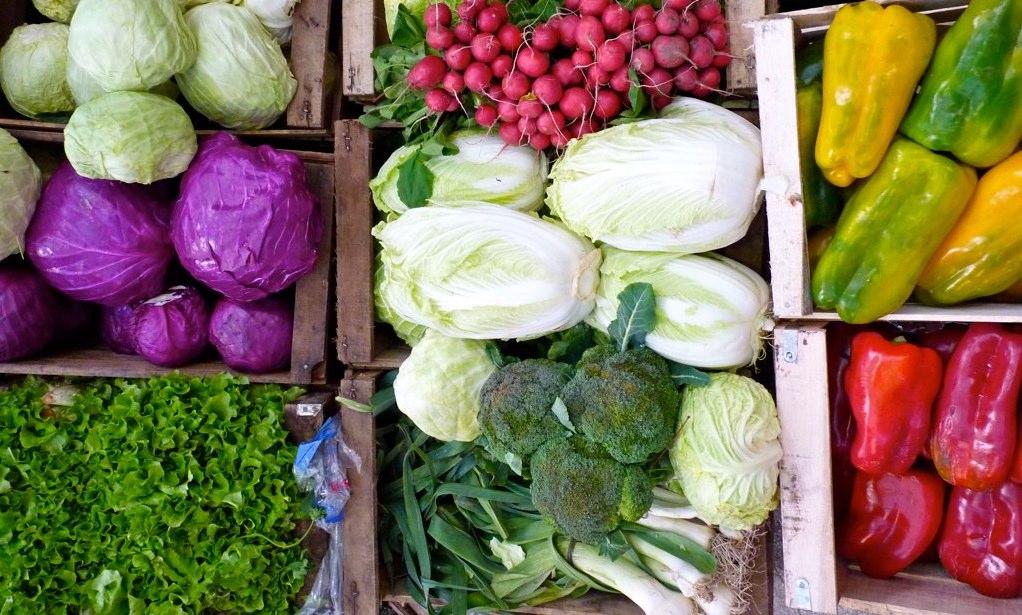 Photo shows a variety of colorful vegetable in bins, perhaps on display at a farmer
