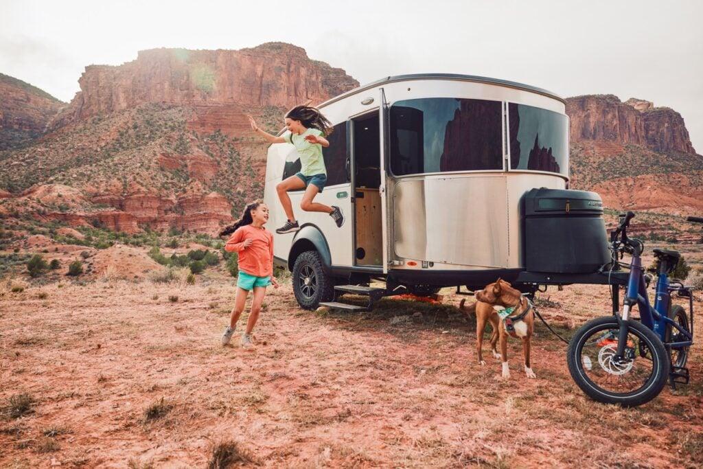 Couple sitting in front of a campfire near Basecamp lightweight travel trailer. photo: Airstream