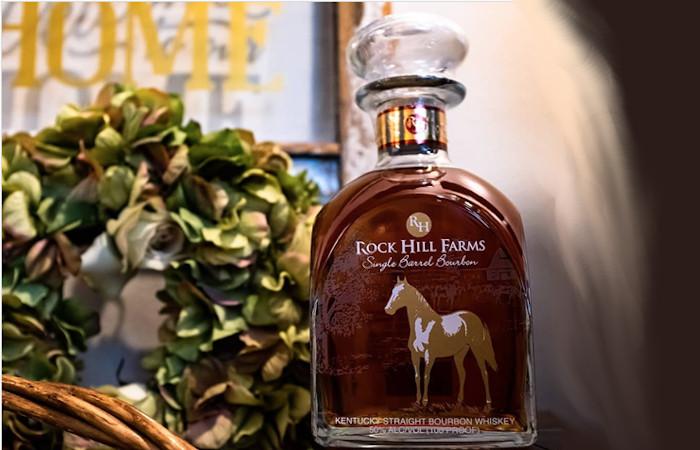 A full bottle of Rock Hill Farms Bourbon placed in front of a green wreath and home decor