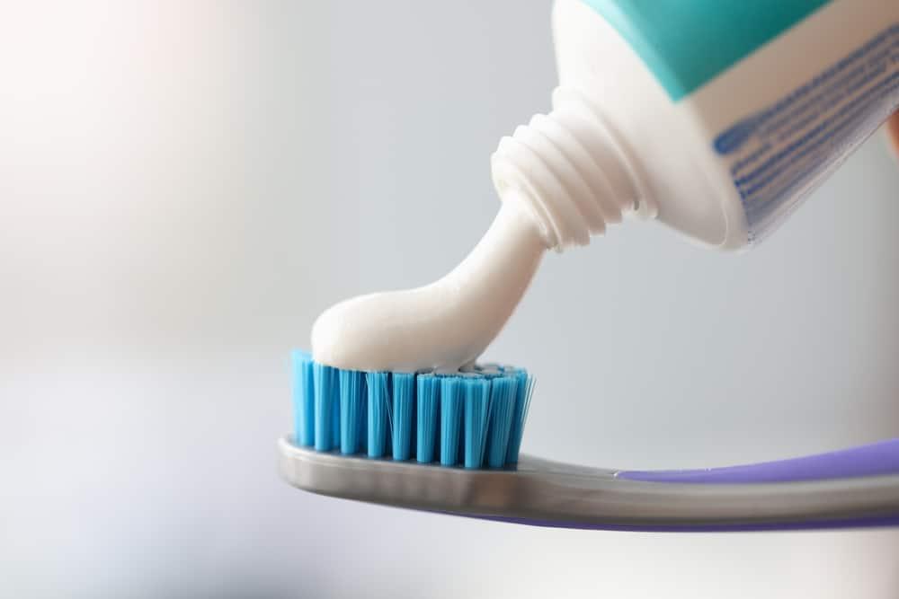 White toothpaste is applied to toothbrush. Oral Care Concept