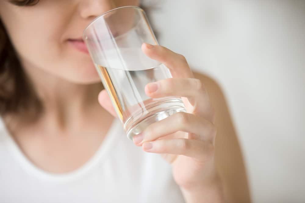 Happy beautiful young woman drinking water