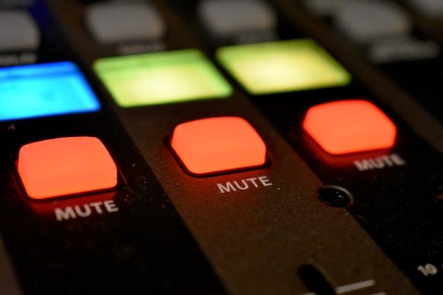 A close-up of a red mute button on an audio device.