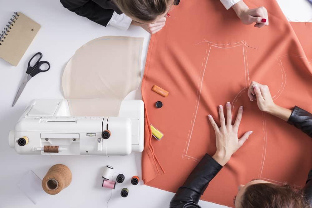 Top view of two girls making a pattern on a red piece of material.