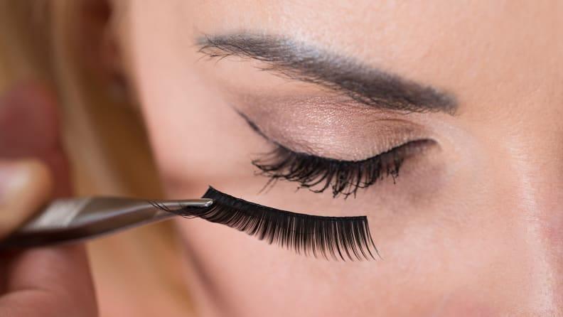 Use your fingers, tweezers, or a designated fake eyelash applicator to place the band of lashes on your eyes.