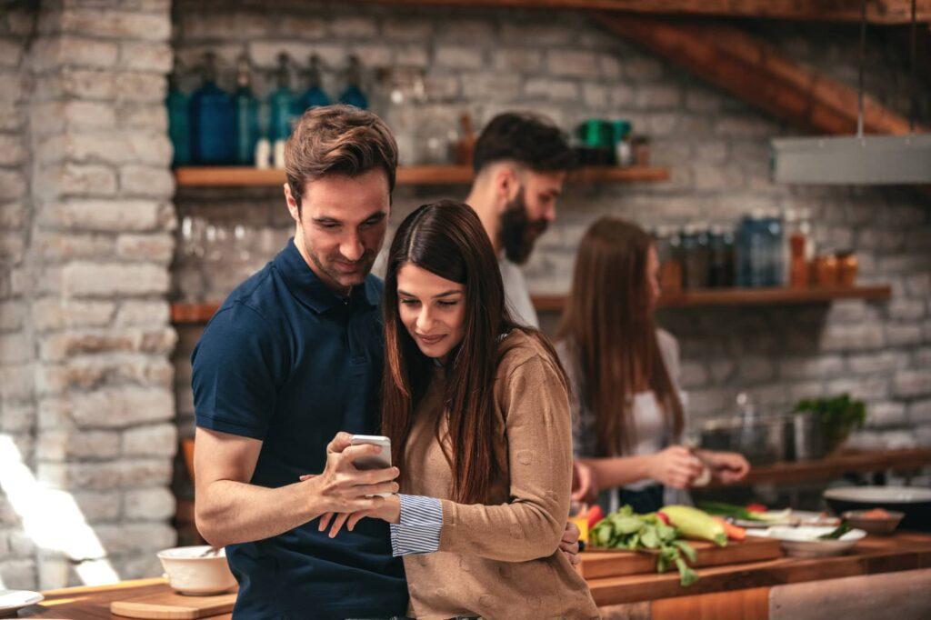 How to unblock someone on Instagram. Young couple looking at phone and smiling.