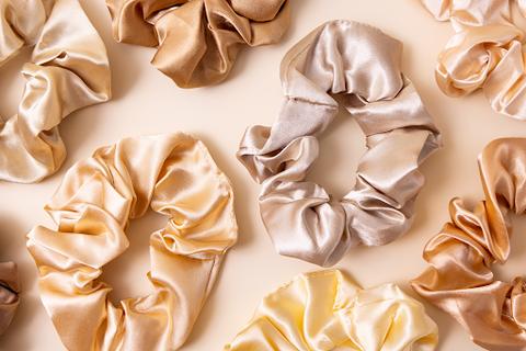 A variety of different colored satin scrunchies from golds to creams