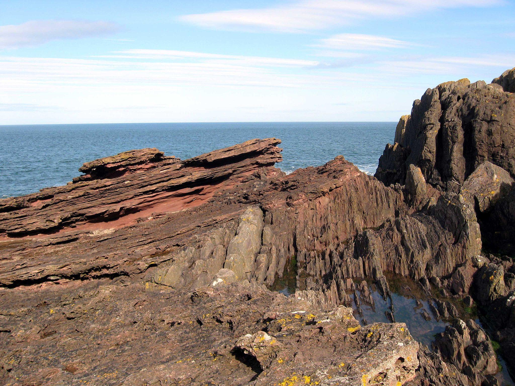 The grey rock is broken and angular within the larger rock.