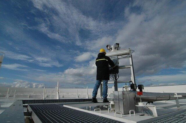 Picture of a man on a roof servicing an industrial air conditioner and HVAC system.