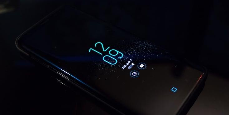 An Android phone with the clock on a dark screen and dark background