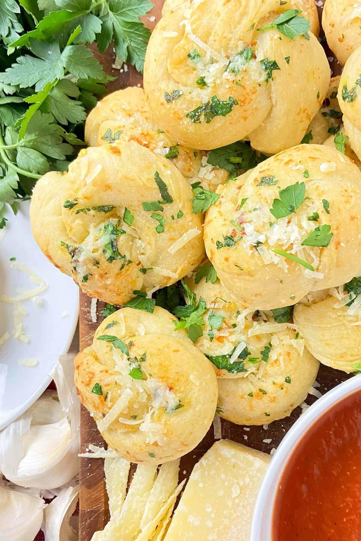 Garlic knots on cutting board with freshly chopped parsley.