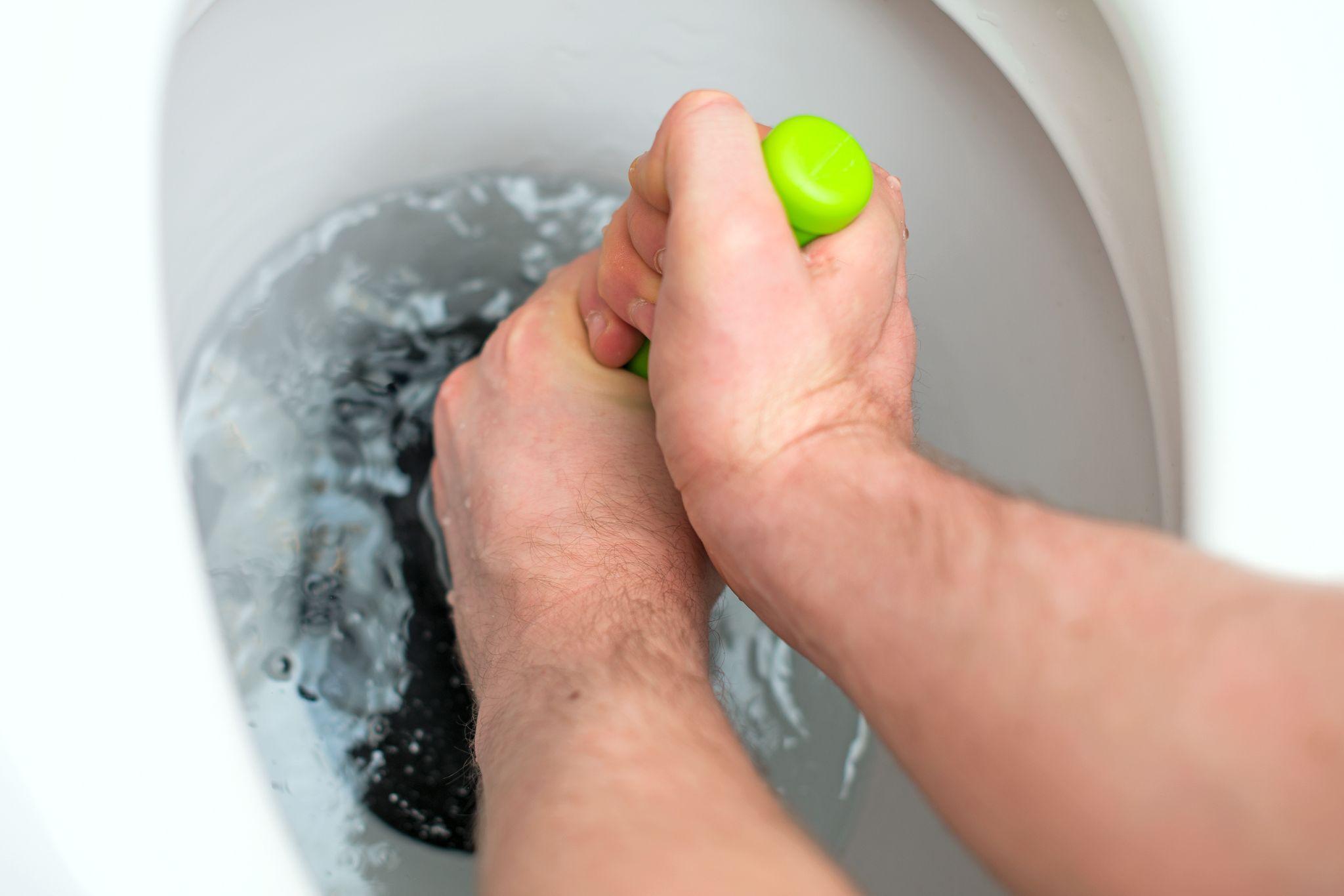 Plumber repairing toilet with hand plunger