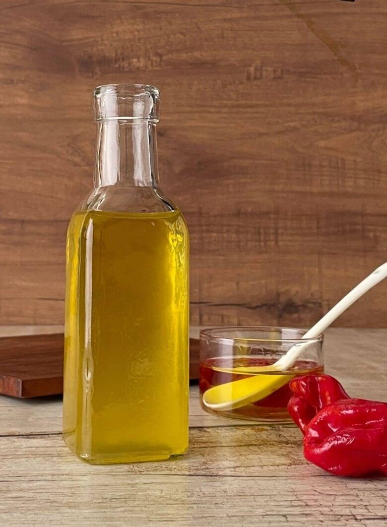 A wooden table with a bottle of olive oil and a spoon.