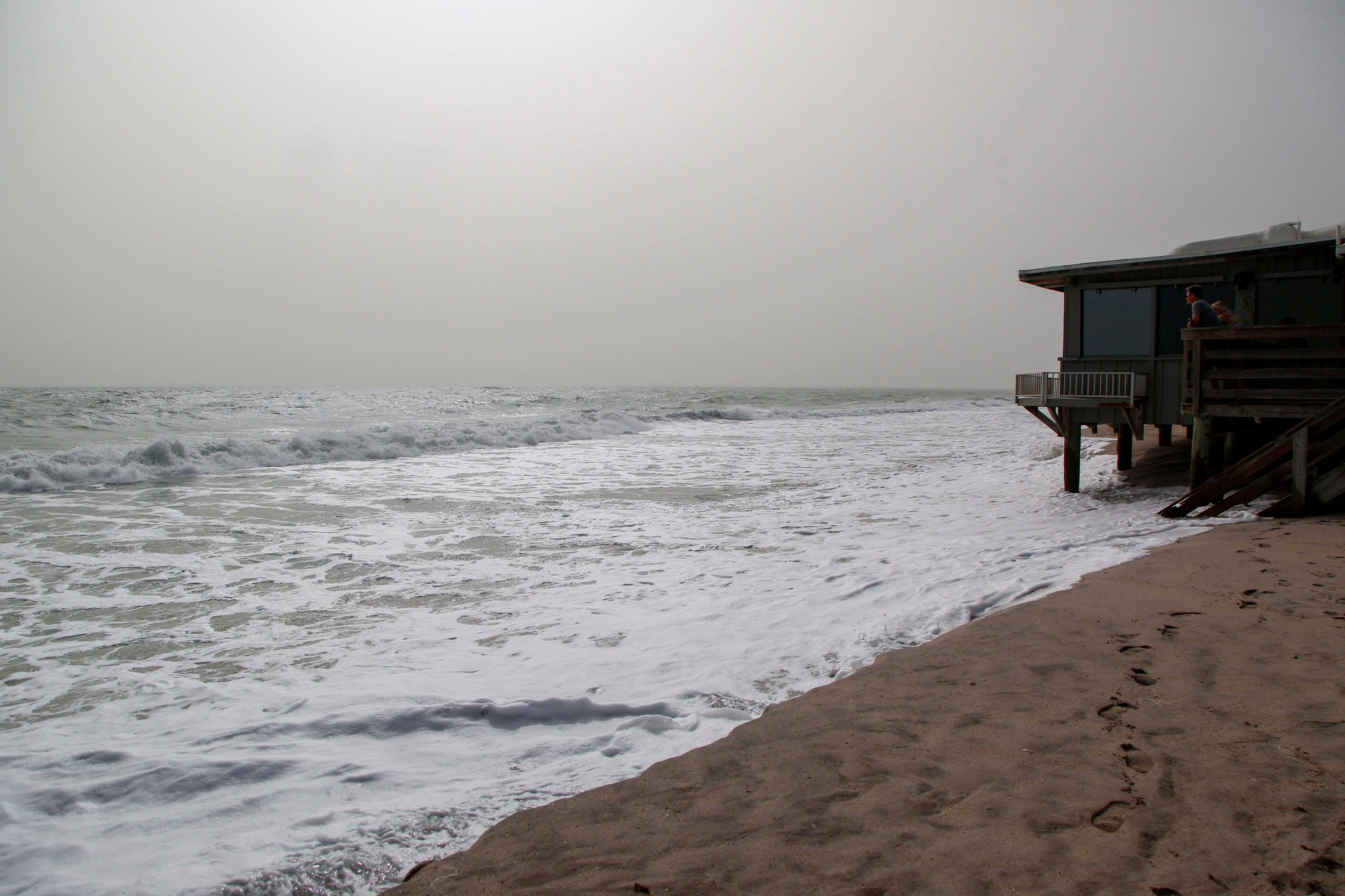 Sections of the beach at Sexton Plaza is seen at high tide, Tuesday, Oct. 3, 2023, during hazy conditions from a wildfire in Quebec, Canada, which made its way down to east central Florida, according to the National Weather Service in Melbourne. Some areas across Florida, especially the Treasure Coast and Orlando areas, may exhibit poor air quality to anyone sensitive to particle pollution. “It