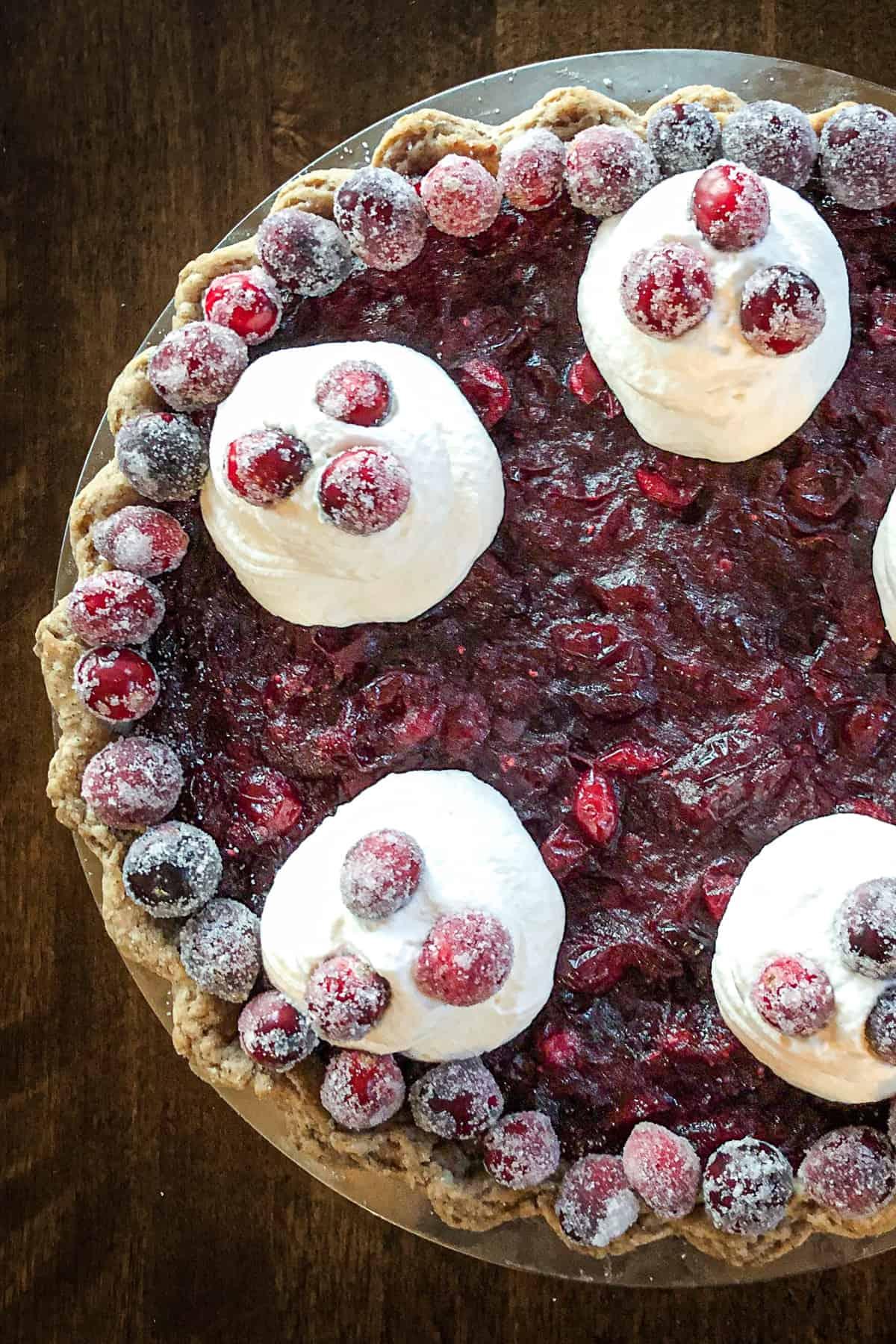 Cranberry vanilla custard pie with whipped cream and candied cranberries.