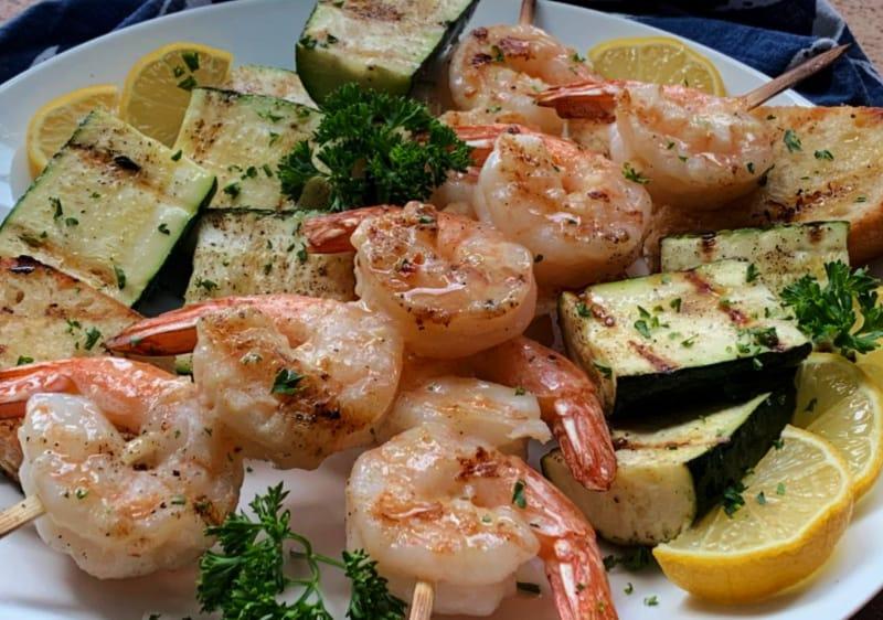 grilled lemon garlic shrimp skewers with lemon wedges and grilled zucchini