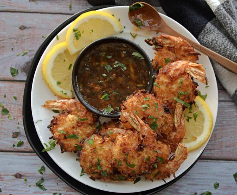 what to serve with coconut shrimp - white plate with coconut shrimp and orange dipping sauce garnished with parsley