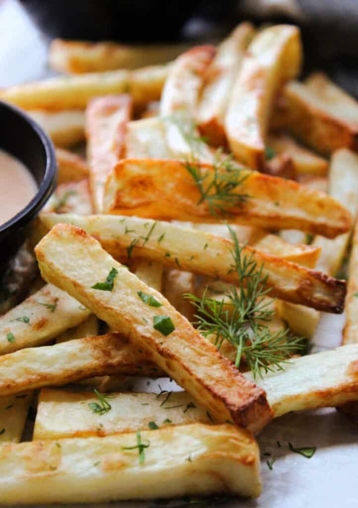 parchment paper with pile of air fryer french fries and dipping sauces